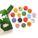 A bunch of shiny round multi-colored pinback buttons coming out of a green felt stocking: Buttons read -- Drunk Uncle, Egg Nog Fog, Star Baker, Sugar Plum Fairy, Lump of Coal, Naughty/Nice, Re-Gifter, Present Peeker, Jewish, Food Coma, Latke Lover, Gay Apparel, Nut Cracker, Fruit Cake, Candy Cane Licker and more