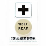 Round 1.25" cream colored pinback button that says WELL READ in black text. Button is on a Social Alert Button backing card.